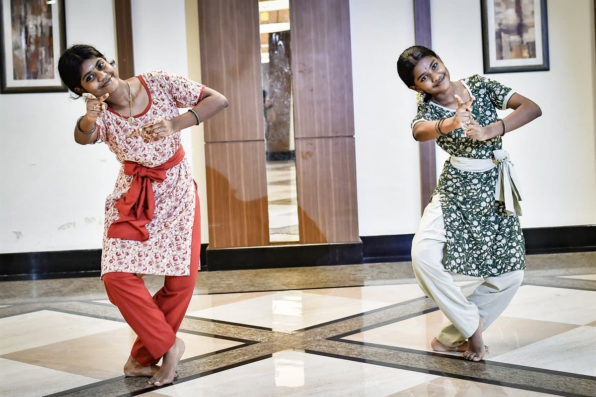 Two students at Yathi Nithi in an abhinaya pose, one with a hand to her cheek and the other reaching out